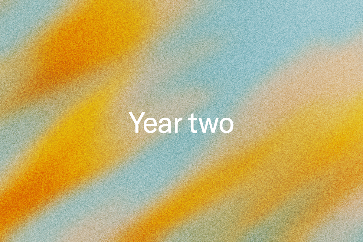 White text "Year two" on a grainy background with diagonal orange, yellow, and blue color gradients.
