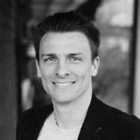 Black and white headshot of a smiling man.