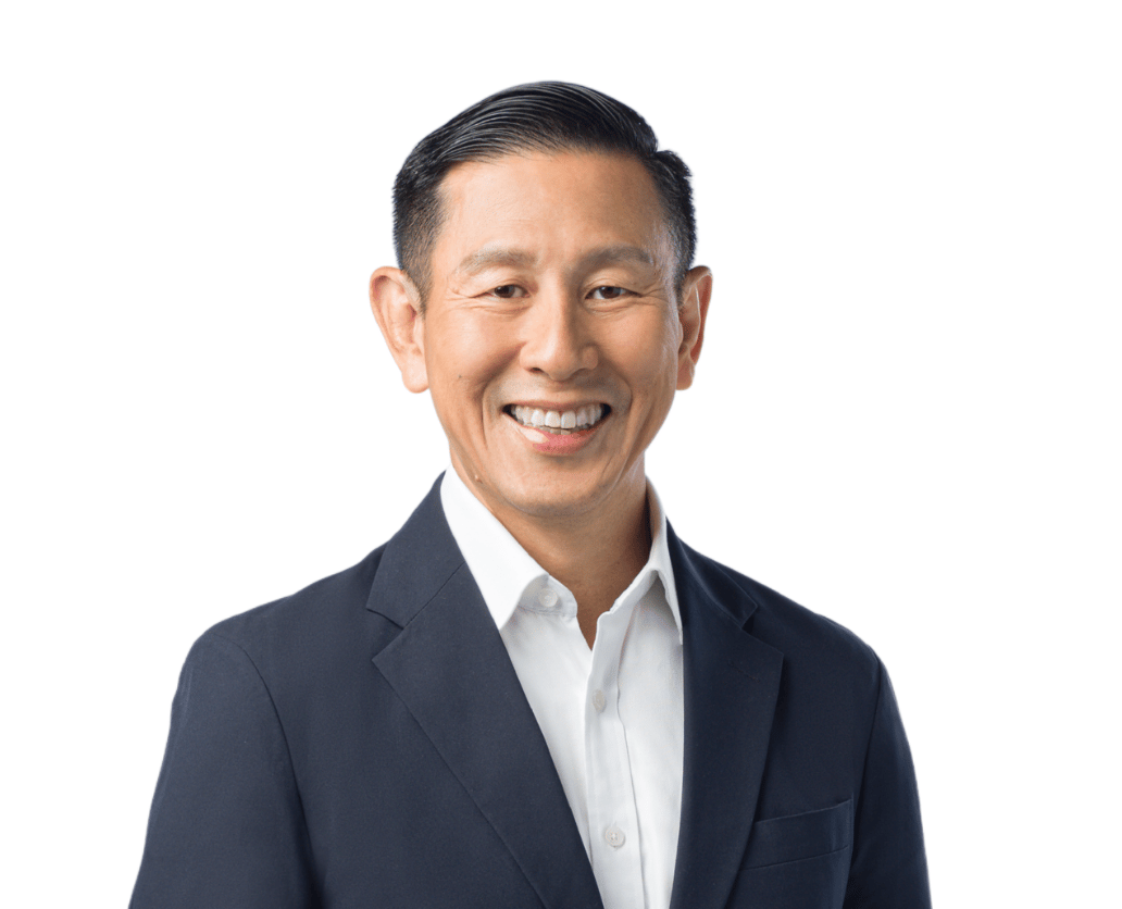 Headshot of an East Asian man in a dark suit jacket and white shirt, smiling against a white background.